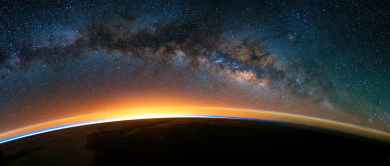 Earths curved horizon from low orbit during golden sunrise with milky way above