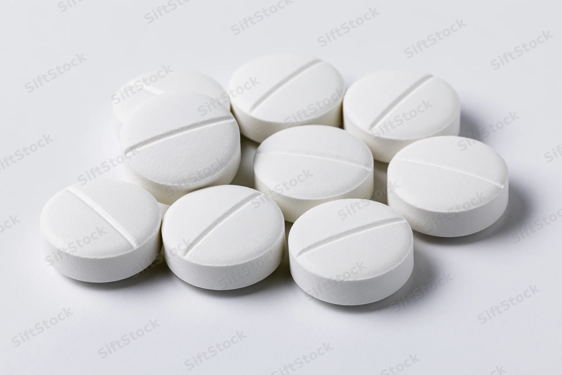 White scored tablets scattered on a plain white surface