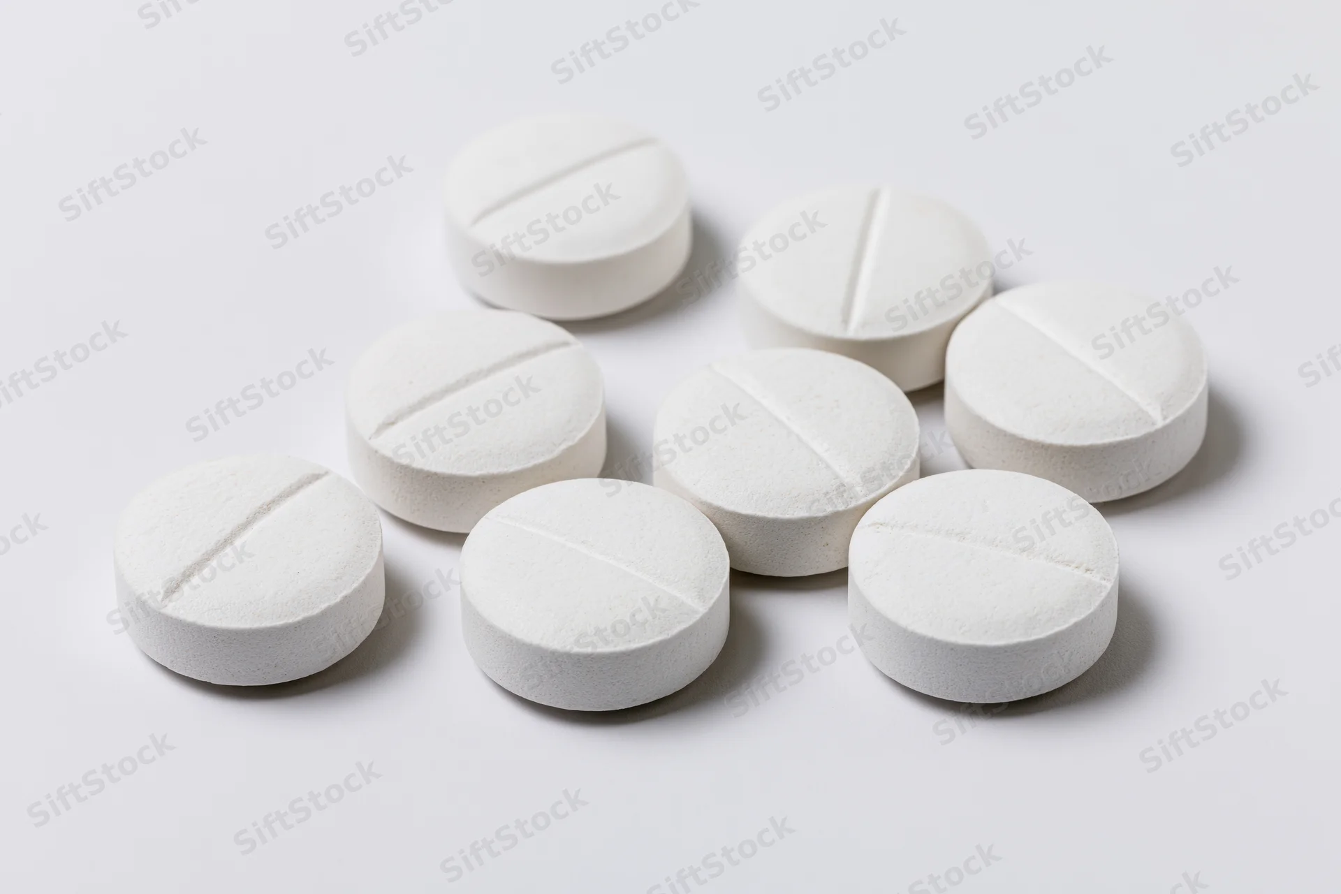 White scored tablets scattered on a plain surface