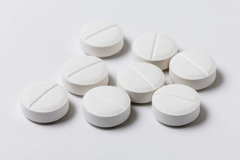 White scored tablets scattered on a plain surface