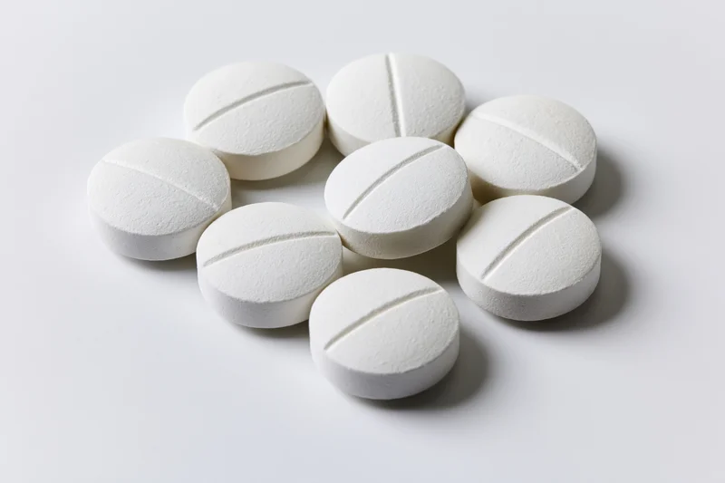 White scored tablets scattered on a plain surface