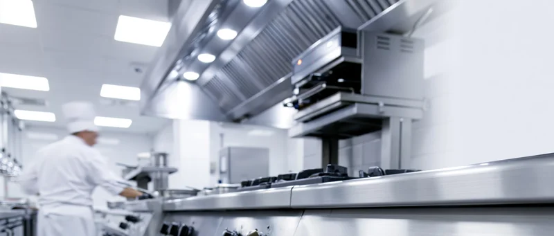 Chef working at stainless steel stove in commercial kitchen interior