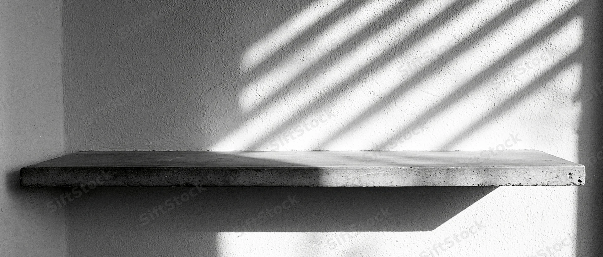 Empty concrete shelf mounted on a textured plaster wall with diagonal sunlight shadows