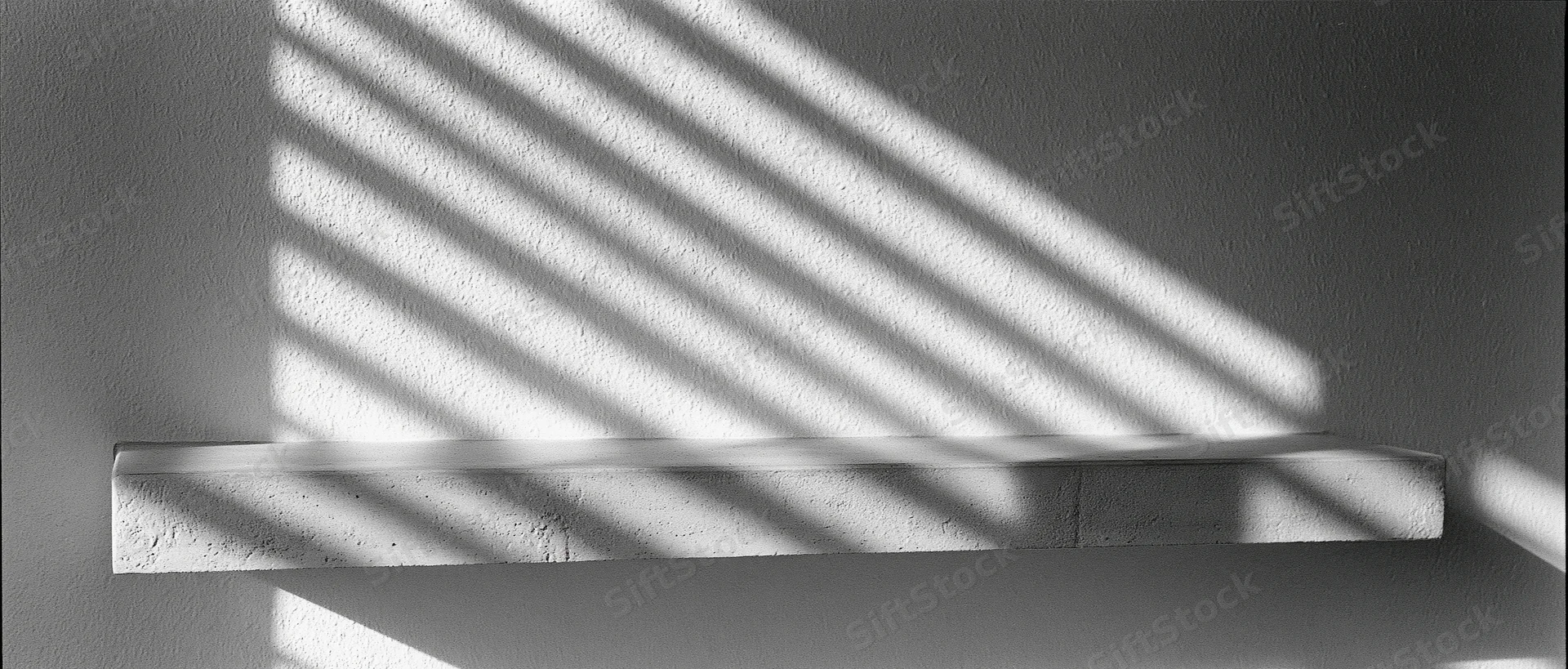 Concrete shelf mounted on textured plaster wall with diagonal sunlight shadows