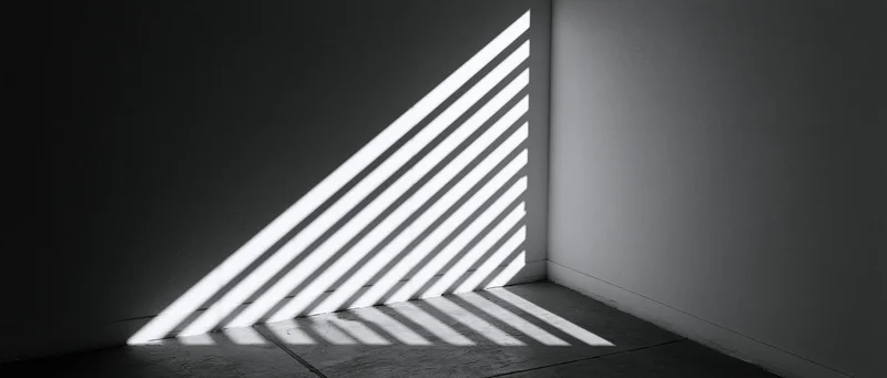 Diagonal light stripes from venetian blind cast on dark room corner wall and floor