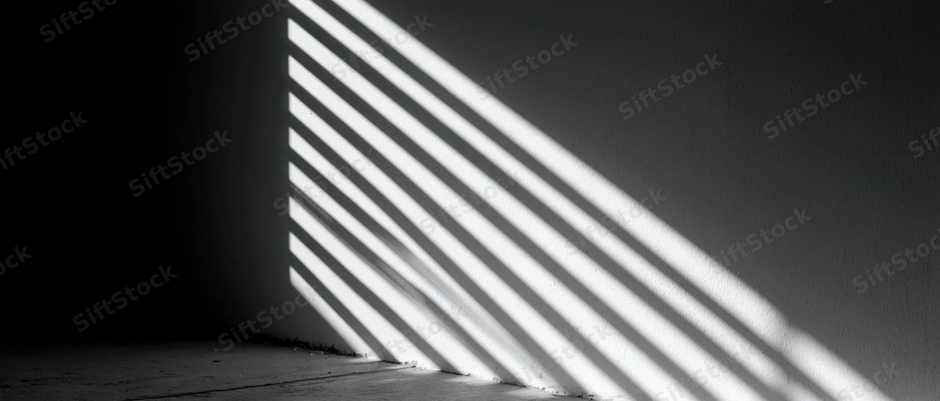 Diagonal light stripes from venetian blind cast on dark wall and floor in empty room corner