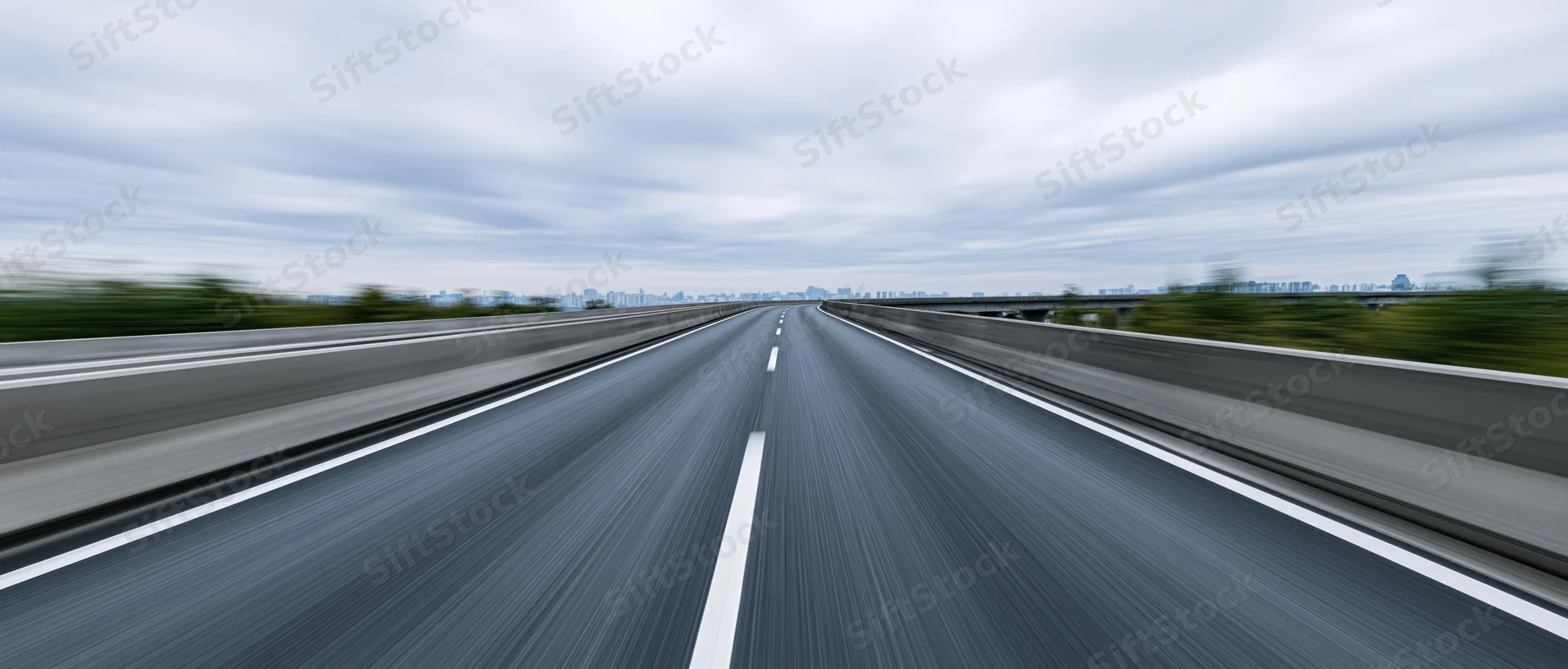 Elevated highway viewed from driver's perspective with motion blur under overcast sky