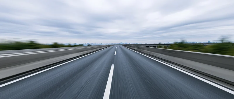 Elevated highway viewed from driver's perspective with motion blur under overcast sky