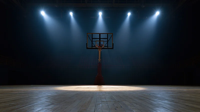 Basketball hoop illuminated by spotlights on an empty indoor court