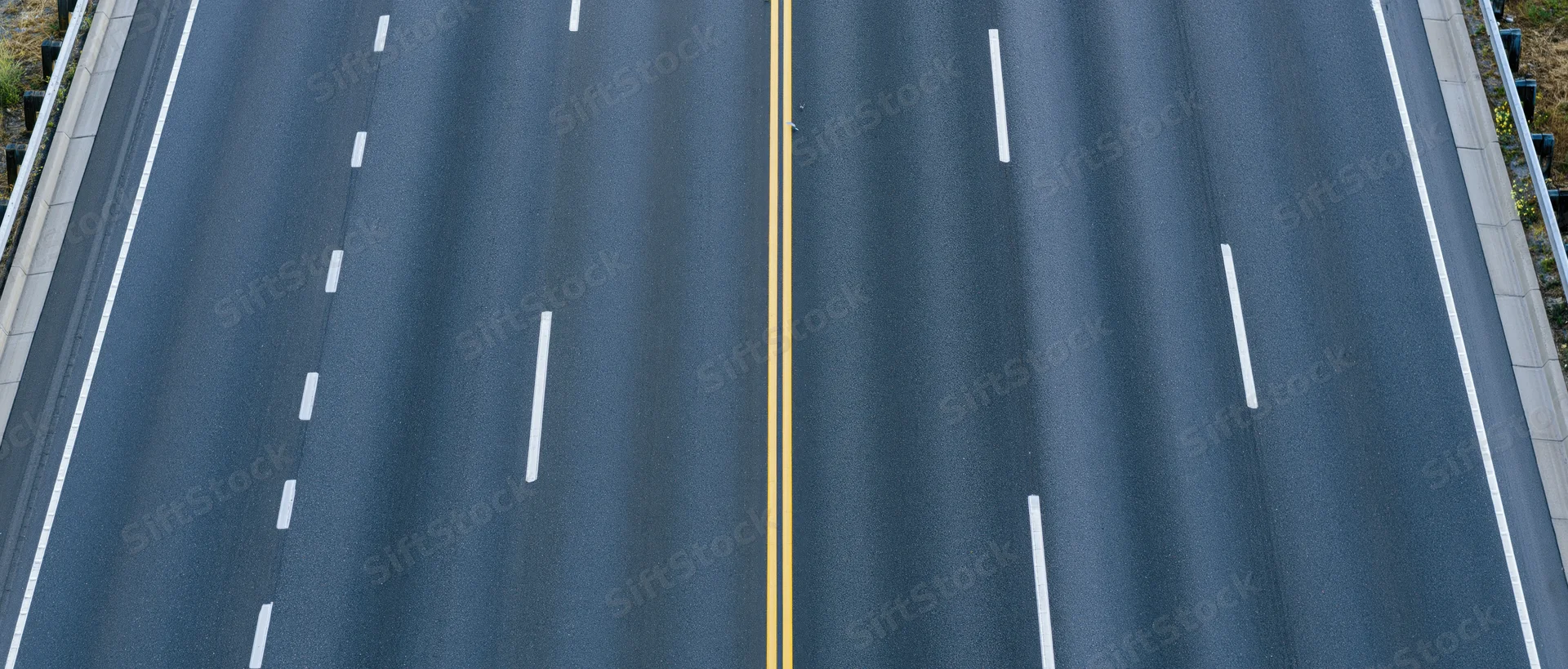 Overhead view of empty multi-lane asphalt highway with white and yellow lane markings