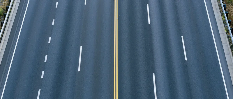 Overhead view of empty multi-lane asphalt highway with white and yellow lane markings