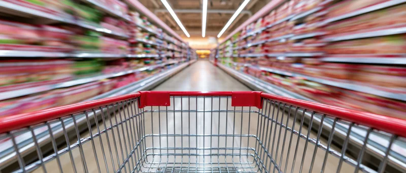 Empty red and chrome shopping cart moving quickly down a supermarket aisle