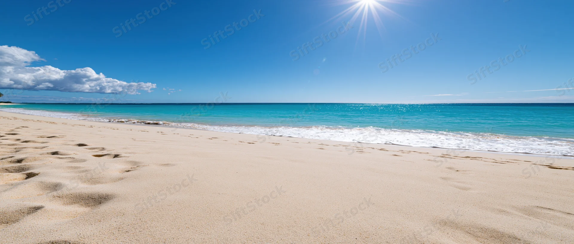 Empty tropical beach with fine pale sand in foreground under bright sun and turquoise ocean