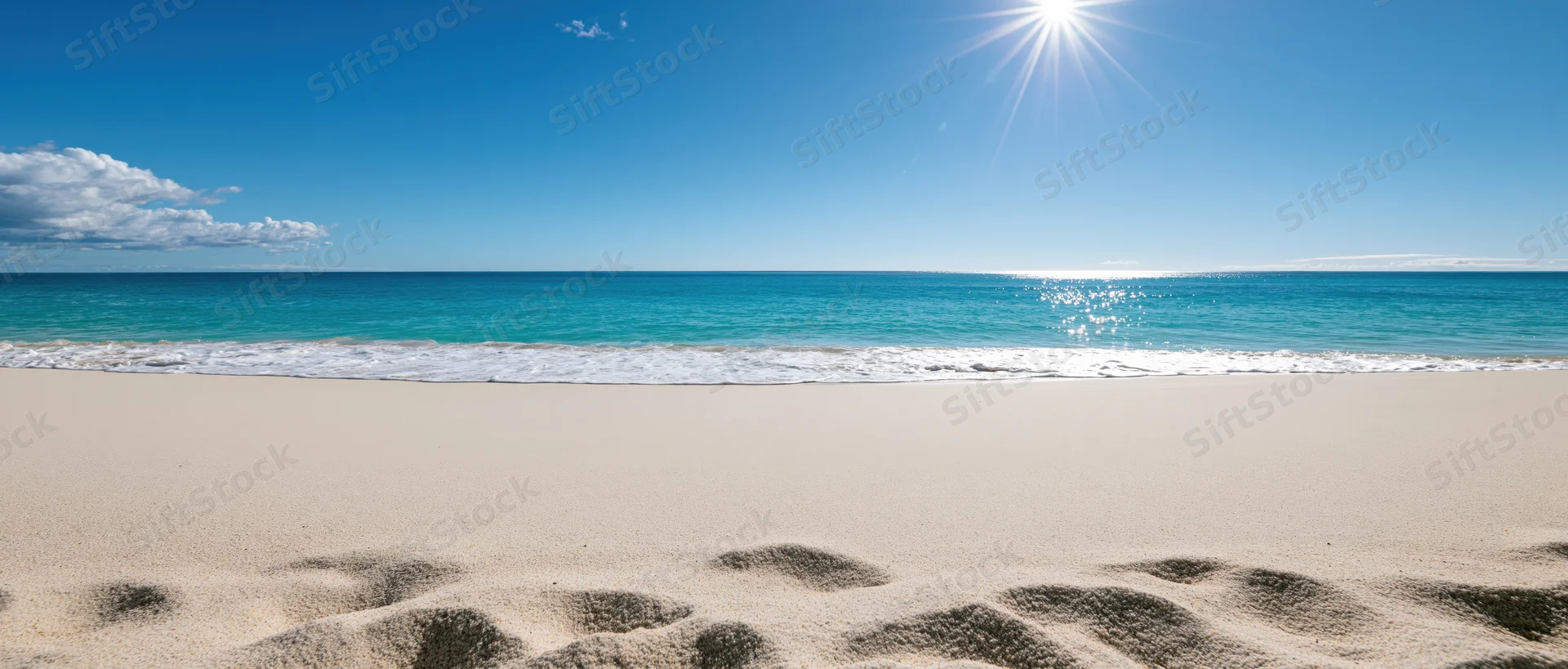 Empty tropical beach with fine pale sand in foreground and turquoise ocean under bright sun