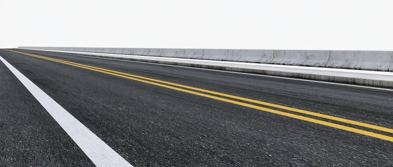 Empty two-lane asphalt road with double yellow and white lines viewed from ground level alongside concrete barrier