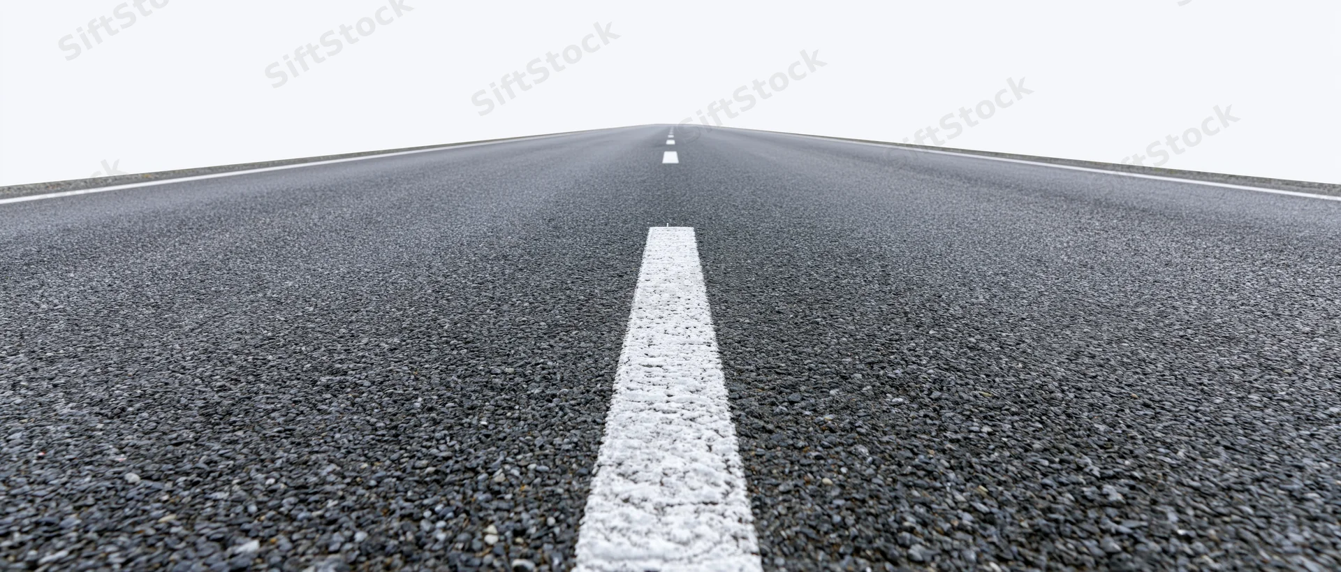 Straight asphalt road with white dashed center line receding into the distance