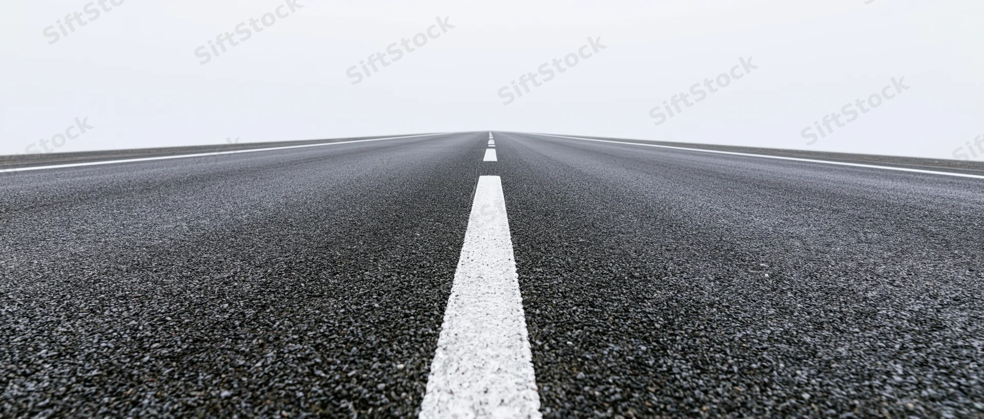 Straight asphalt road with white dashed center line receding into the distance
