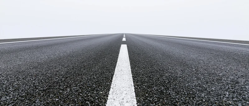 Straight asphalt road with white dashed center line receding into the distance