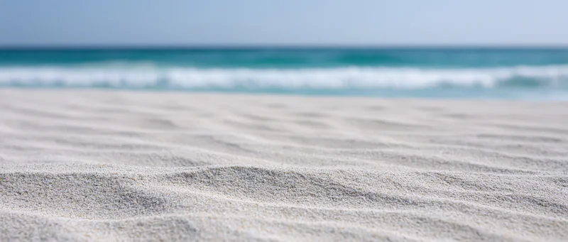 Rippled white sand in foreground with ocean waves in background