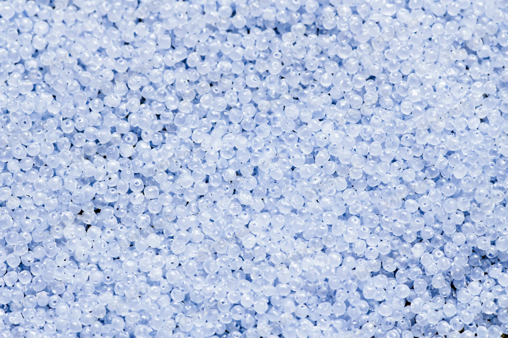 Close-up of translucent blue plastic beads covering a flat surface