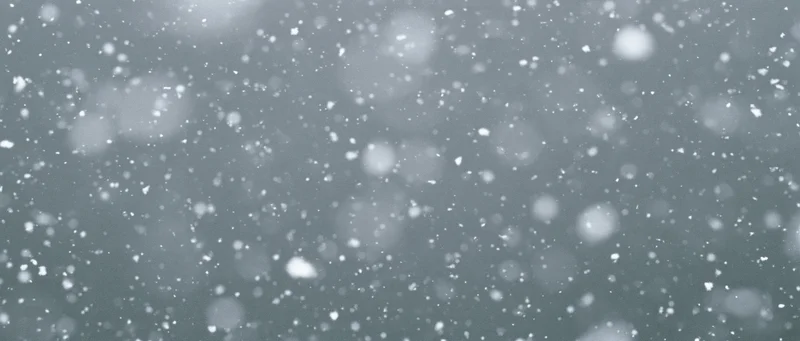 Snow particles falling midair against a grey background