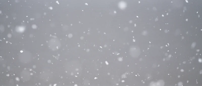 Snow particles falling midair against a grey background