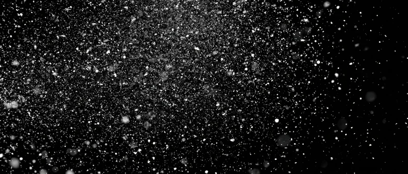 Snow particles falling midair against a black background