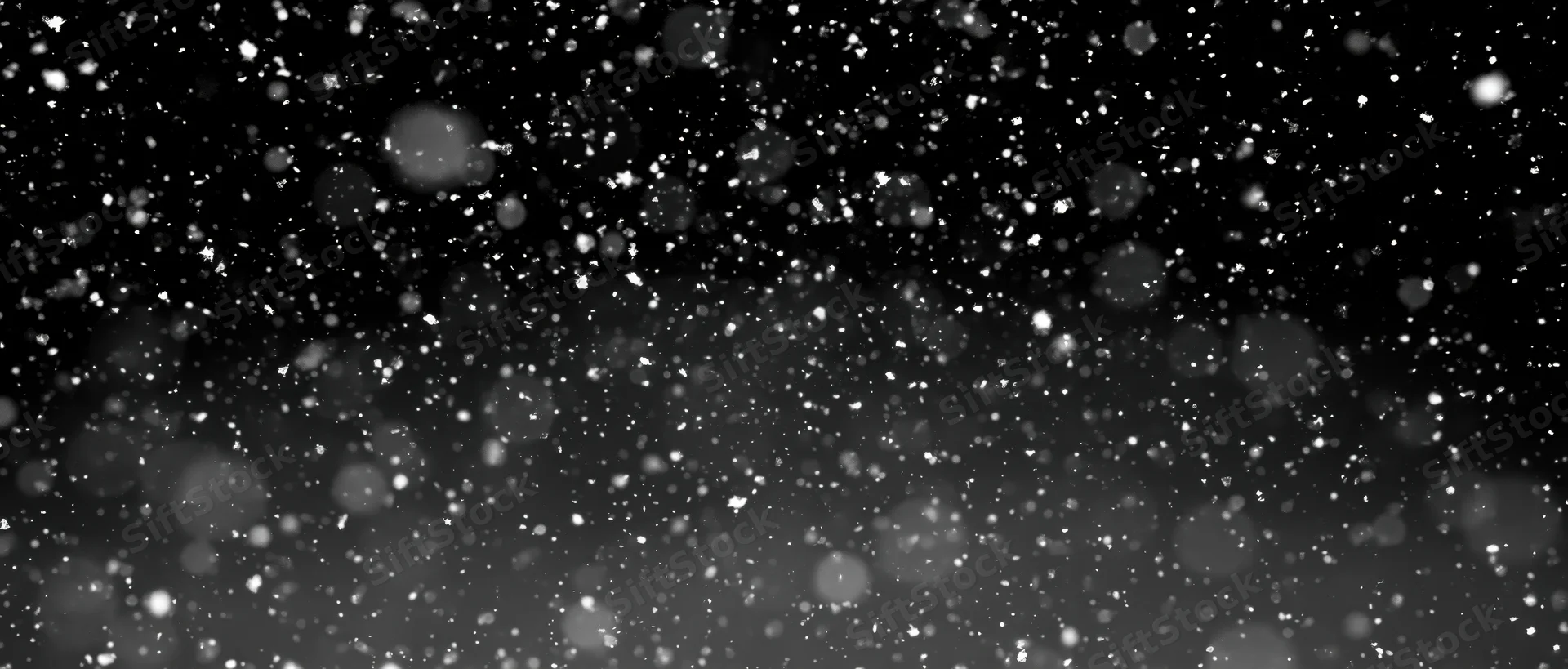 Snow particles falling midair against black background