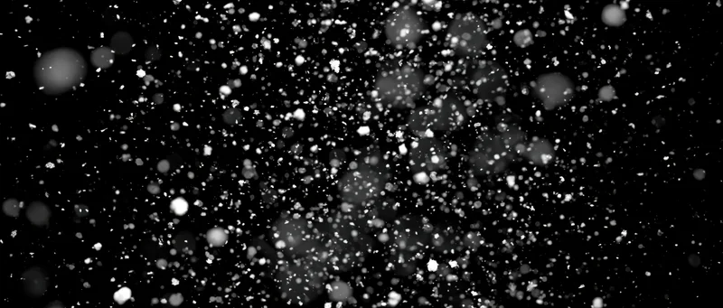Snow particles falling midair against black background