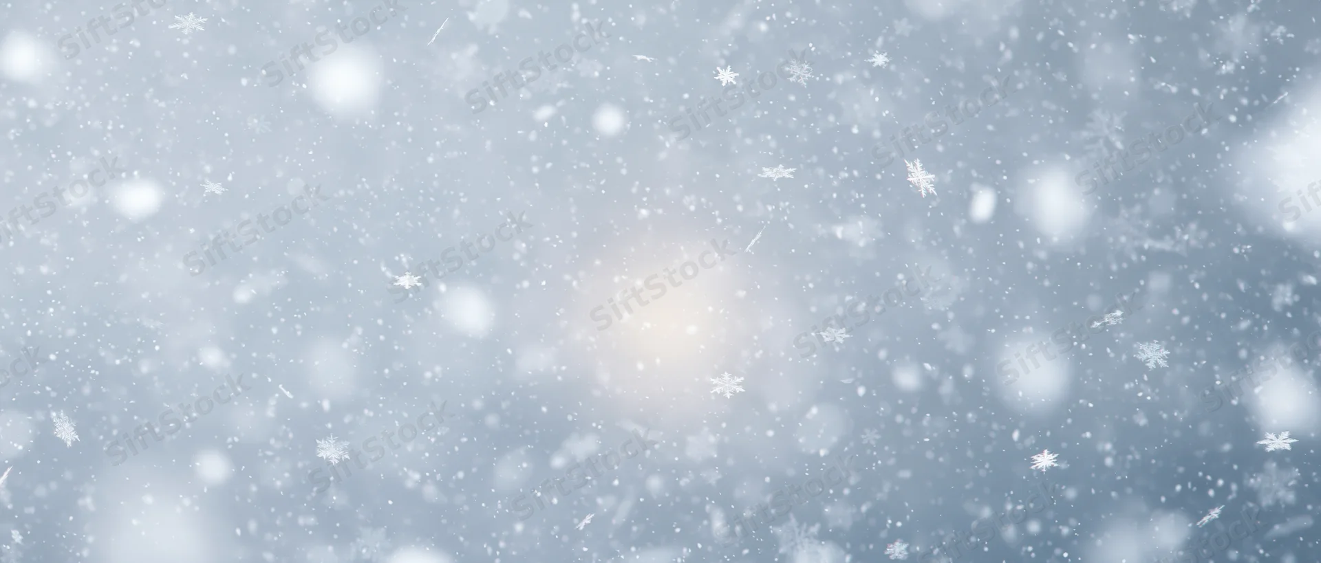 Snowflakes falling and drifting in pale sky with soft light and bokeh effect
