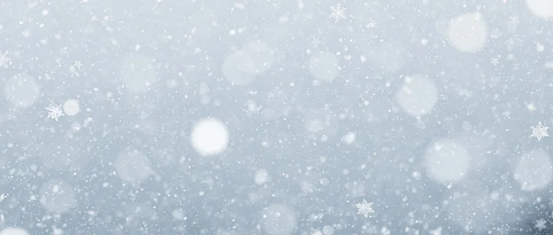Falling snowflakes and soft bokeh particles scattered across a light blue winter sky