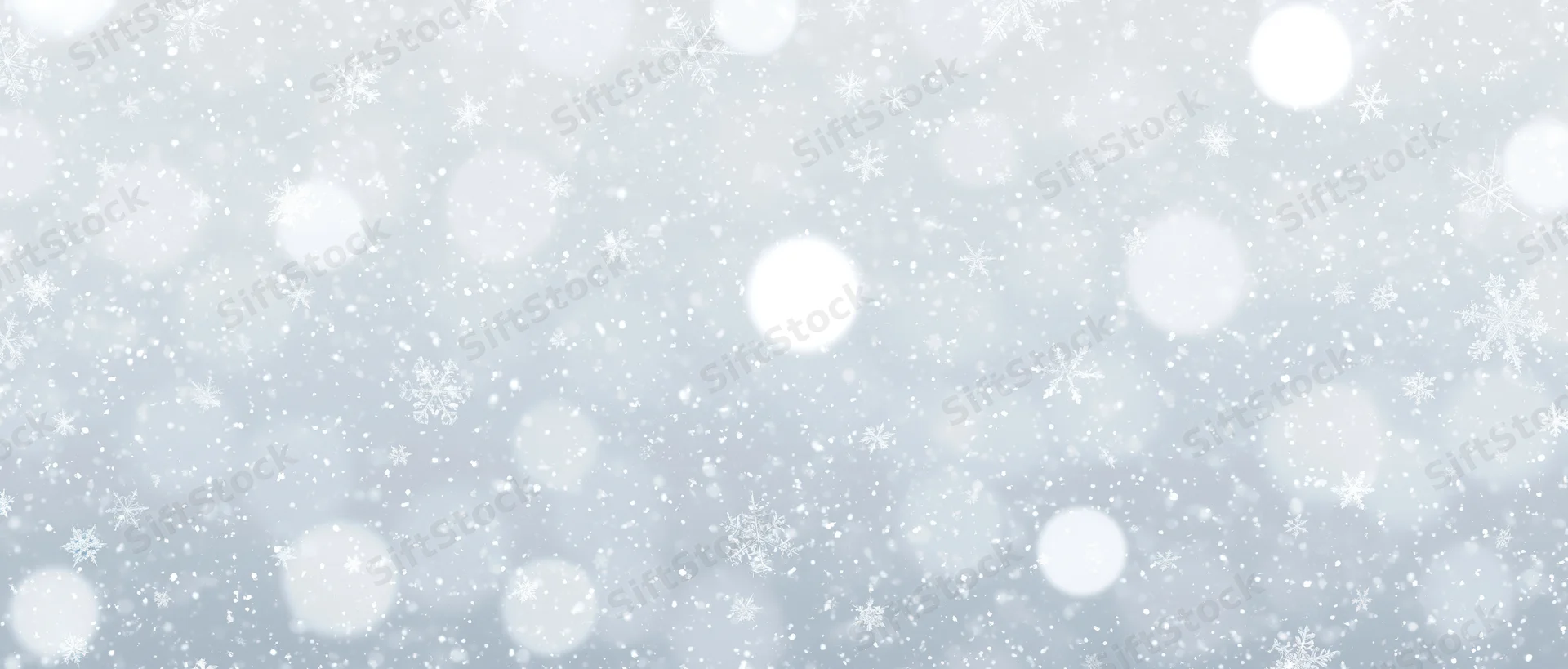 Falling snowflakes and soft bokeh lights scattered across a white winter background