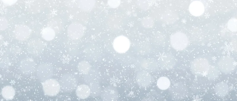 Falling snowflakes and soft bokeh lights scattered across a white winter background