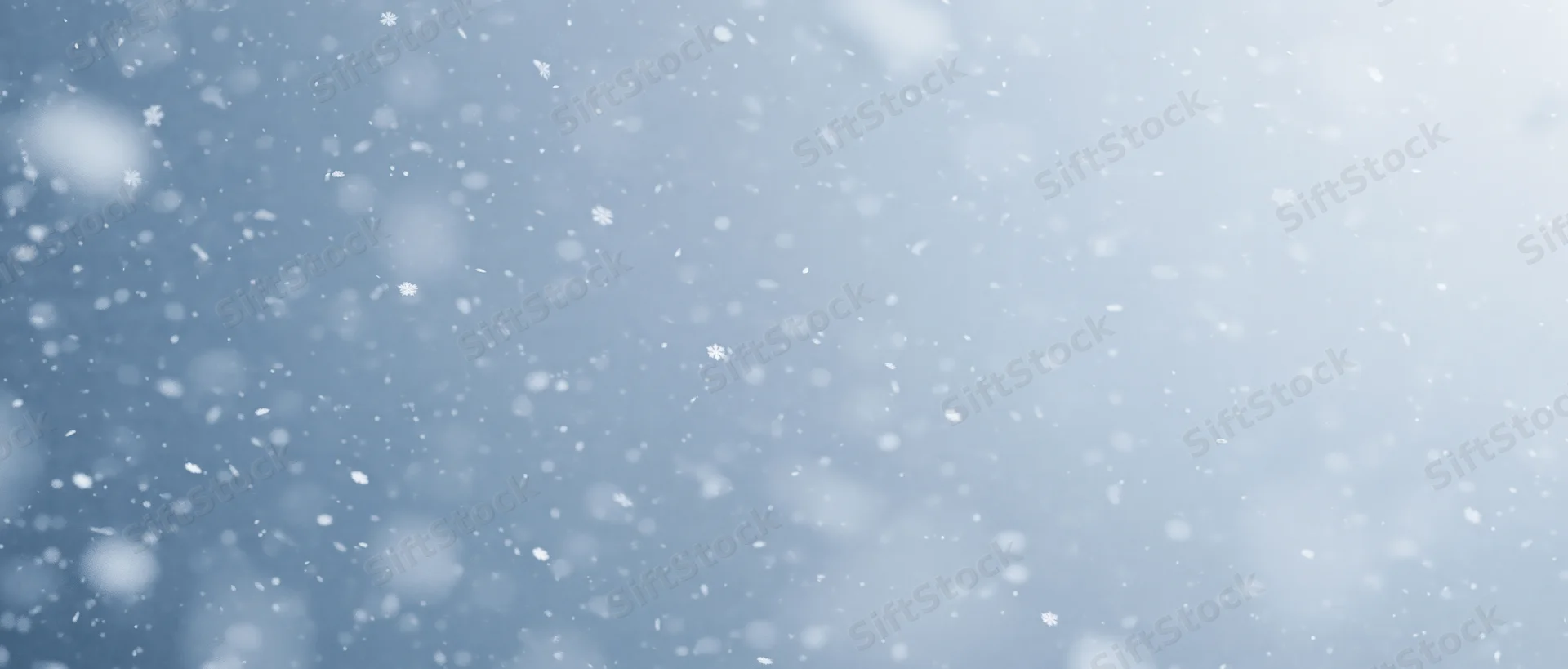Snowflakes falling through a pale winter sky with soft focus and bokeh effect