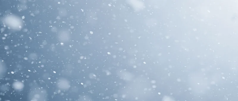 Snowflakes falling through a pale winter sky with soft focus and bokeh effect