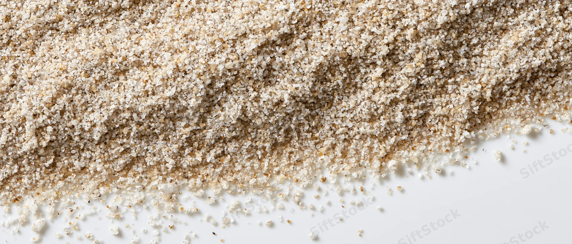 Fine dry sand granules spread across white surface tapering to edge