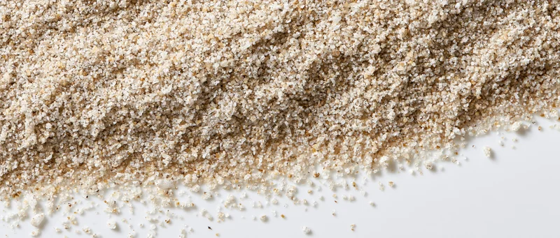 Fine dry sand granules spread across white surface tapering to edge