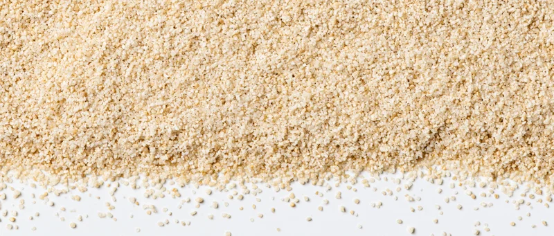 Fine dry sand granules spread across the top of a white surface tapering downward