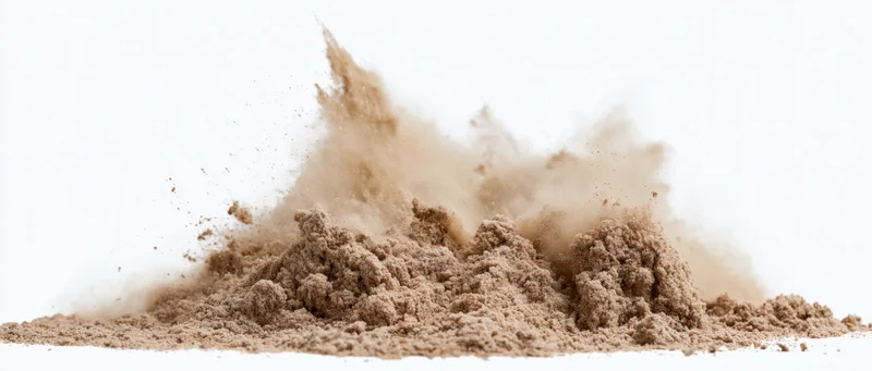 Fine dry sand bursting into airborne particles against white background