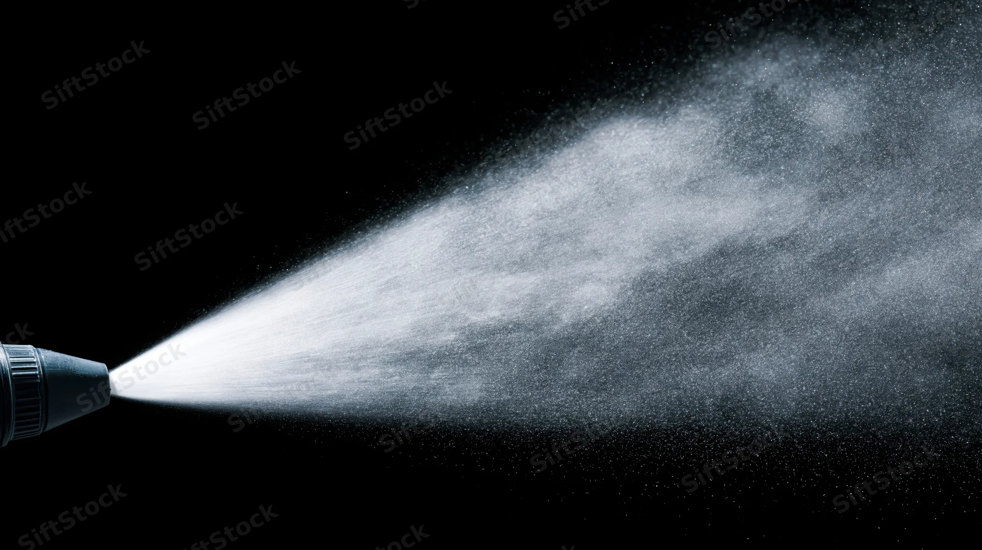 Fine water mist spraying horizontally from a nozzle against black background