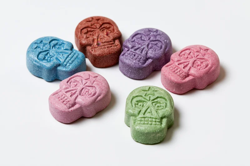 Skull-shaped pressed tablets arranged loosely on white