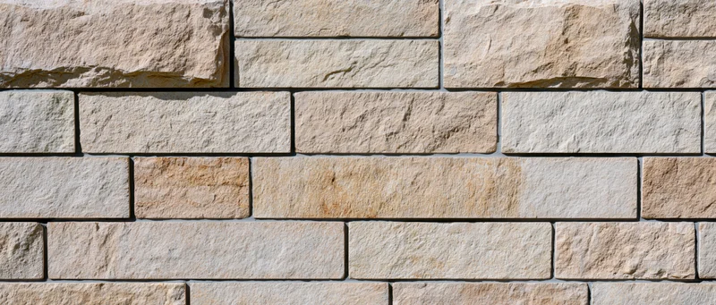 Flat exterior wall covered in irregularly sized cut sandstone blocks arranged in horizontal rows
