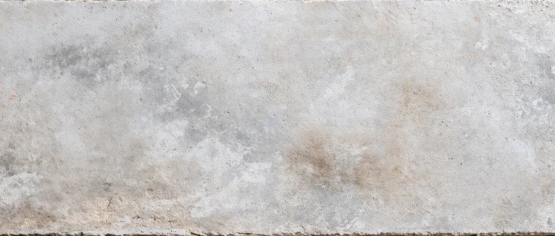 Close-up of a weathered concrete wall surface with rough texture and neutral tones