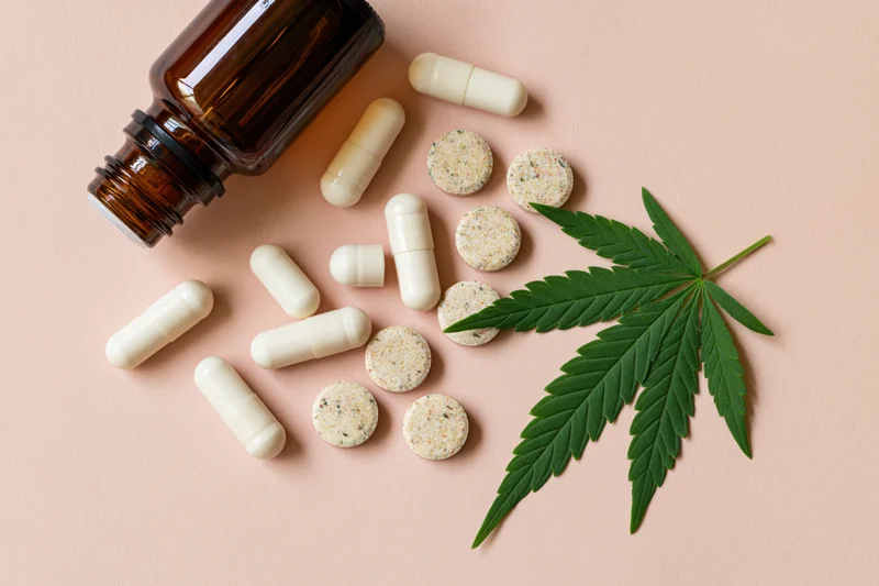 Cannabis leaf and cbd wellness products arranged on pale blush background