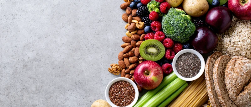 Assorted healthy foods arranged along the right side of a gray surface