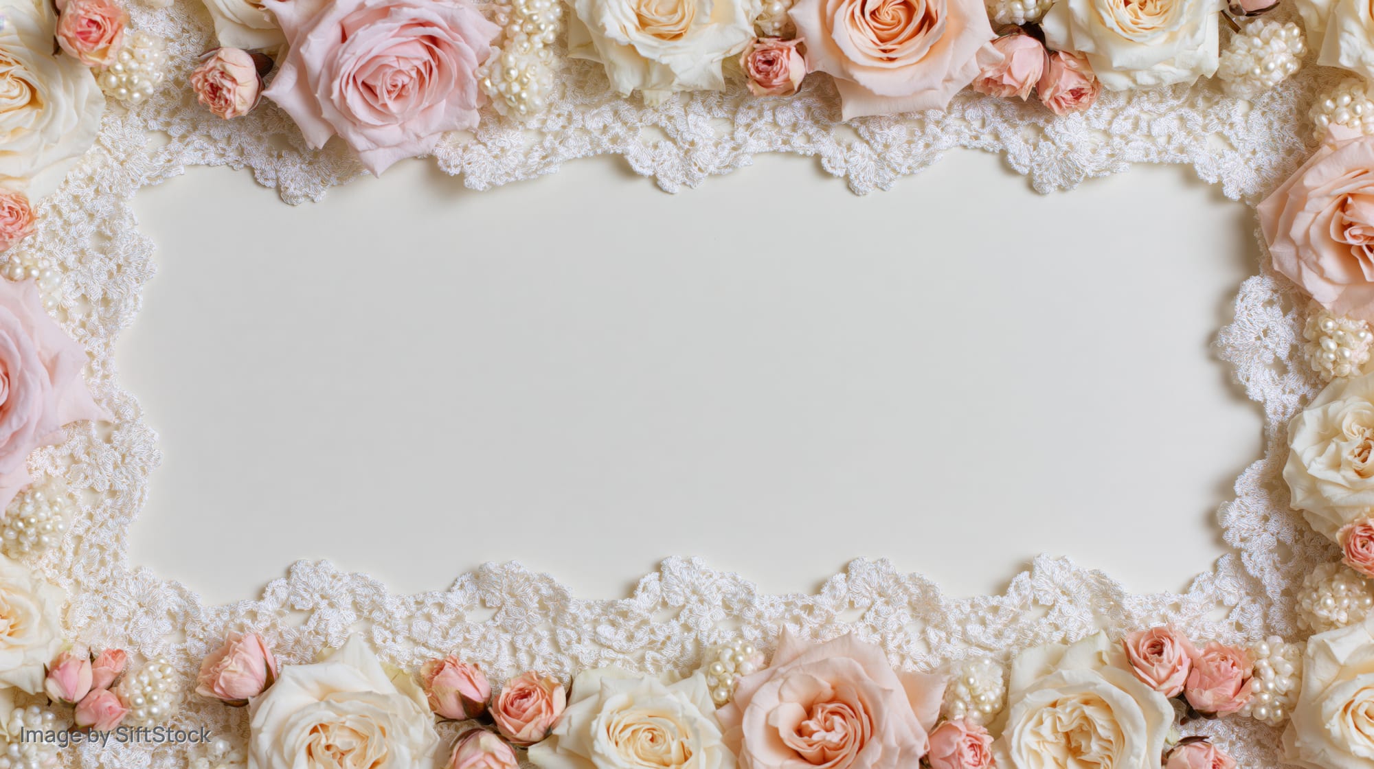 Blush and cream roses with white lace trim arranged in a frame around a blank center space