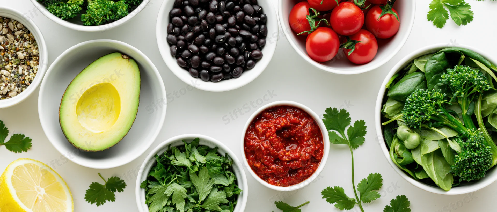 Fresh salad ingredients arranged in white ceramic bowls on a flat surface