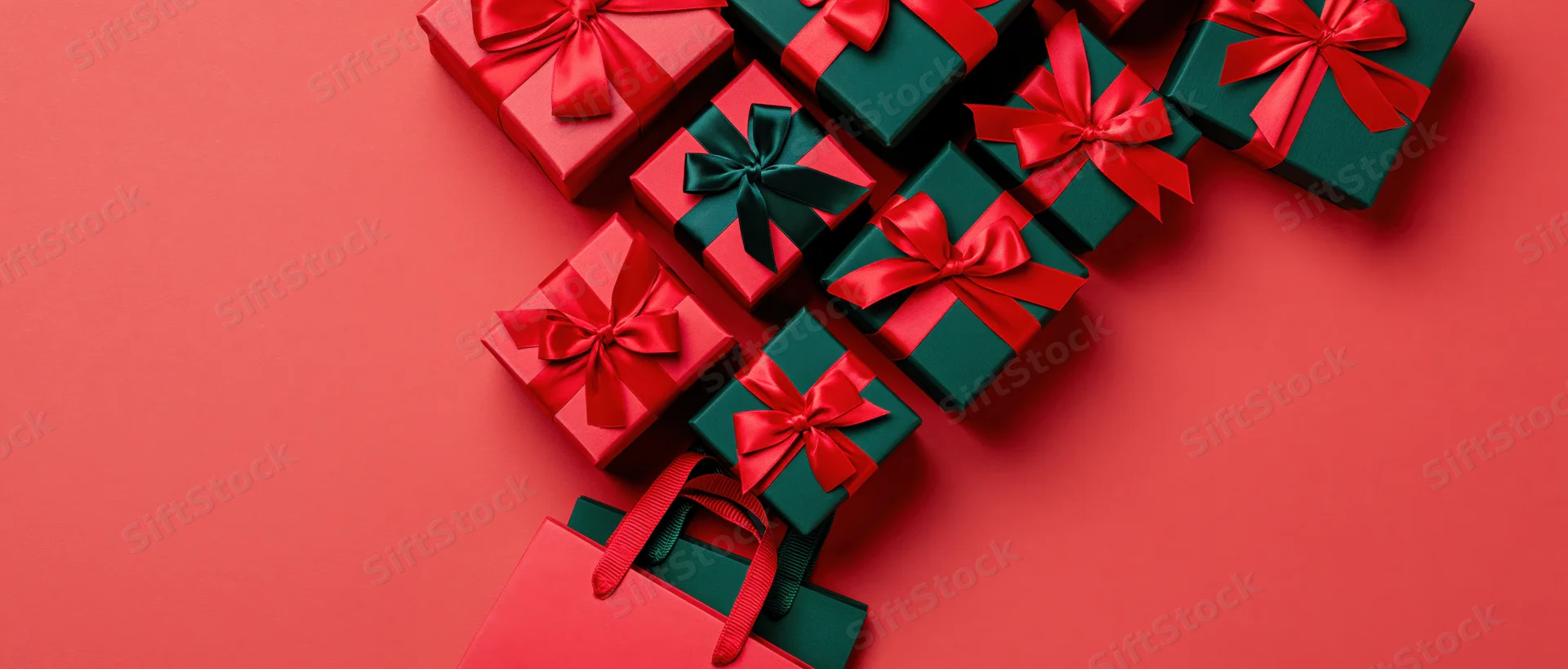 Red and green gift boxes with satin ribbons arranged on a red surface