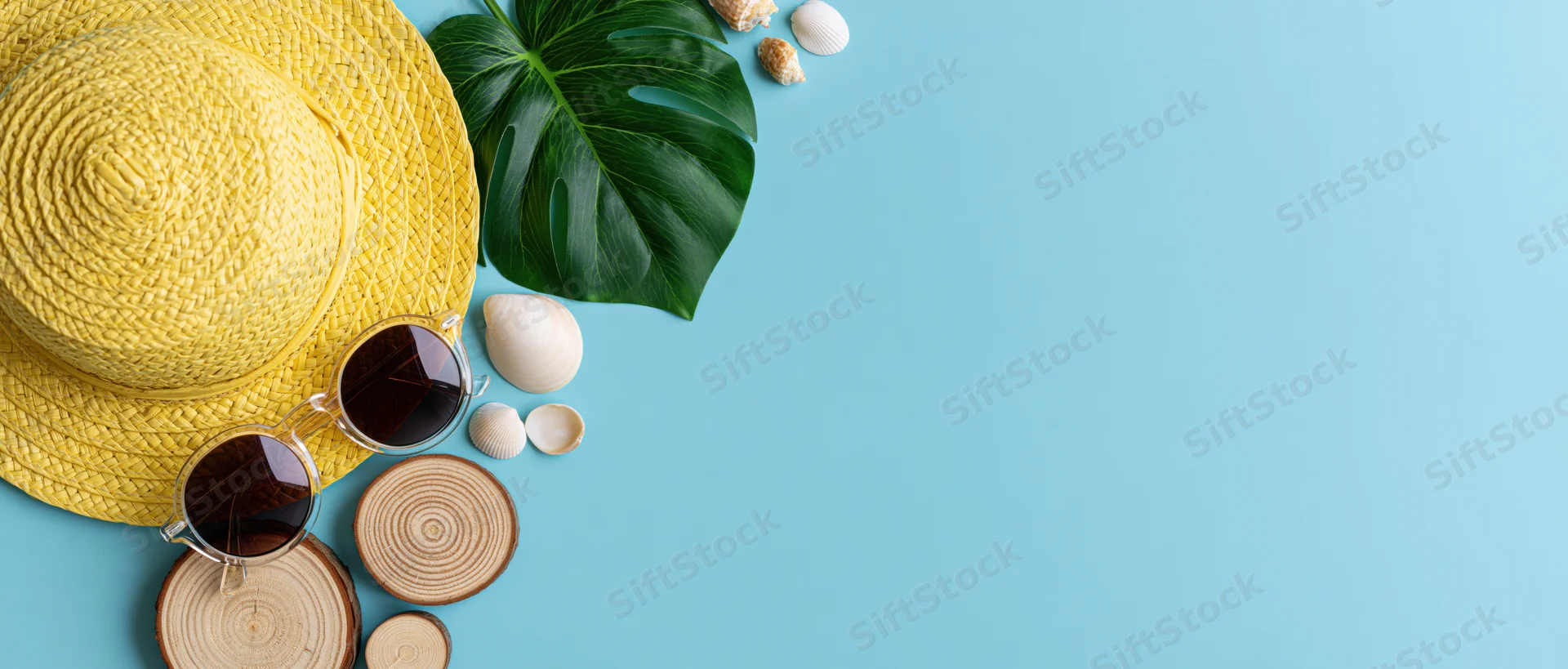 Summer beach accessories arranged in flat lay on blue background with copyspace