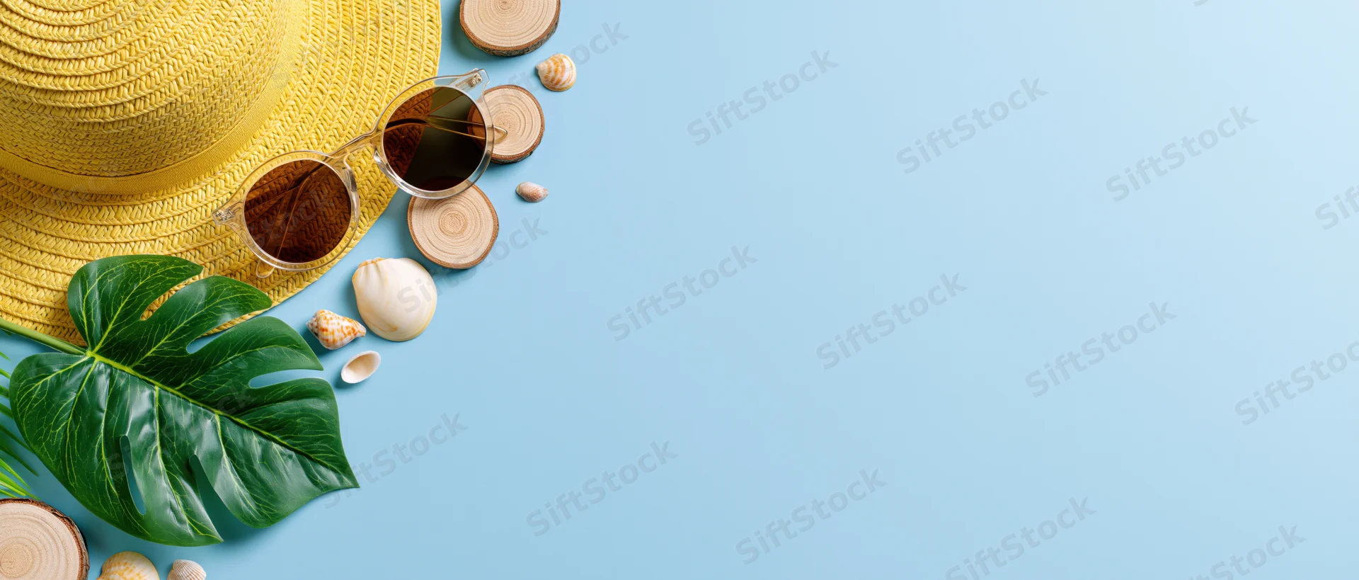 Summer beach accessories arranged in flat lay on blue background with copyspace